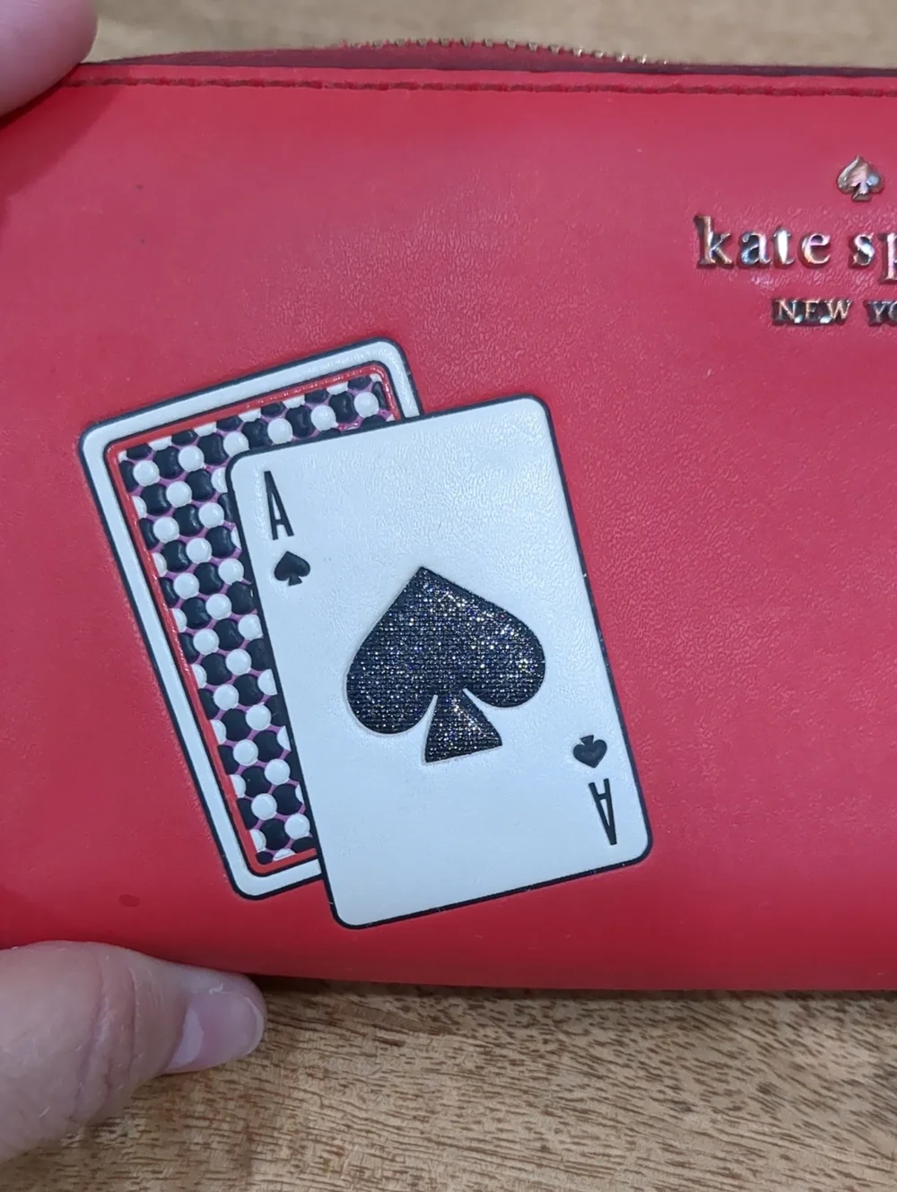 Kate Spade red zip-around wallet with Ace of Spades patch